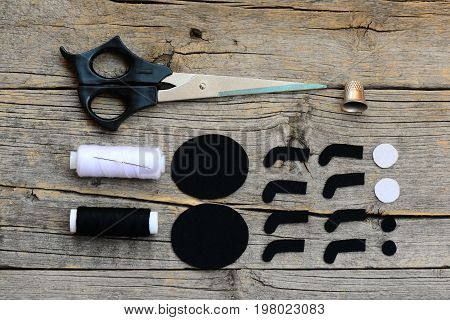 Making a Halloween felt spider decoration. Cut black and white felt details to create Halloween spider toy. Step. Craft supplies on a wooden table. Halloween spider crafts tutorial for kids. Top view