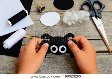 Small child holds a felt spider toy in his hand. Child made a Halloween felt spider crafts. Sewing workshop concept. Teaching a child to sew by hand