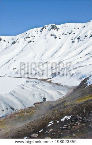 Helicopter from the hot springs on the shore of Karymsky lake in spring in Kamchatka Russia