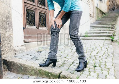 Senior walking through city, suffering from knee pain