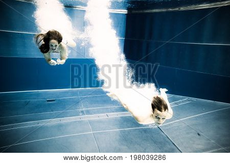 a young couple is jumping into the water from a diving plattform