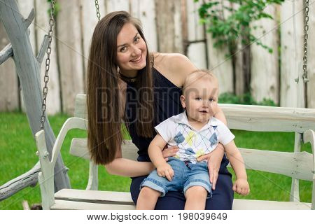Happy woman playing with her baby that siting on her knees