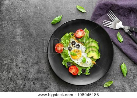 Plate with over hard fried egg and vegetables on dark table