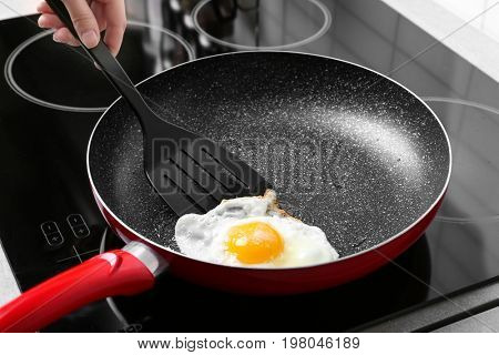 Hand of woman cooking over hard fried egg using spatula