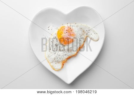 Plate with over hard fried egg on light background