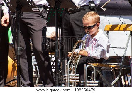 Buchlovice Czech Republic July 29 2017: Little boy plays trumpet at folk festivities. Gifted child. Traditional farmers harvest celebrations of garlic