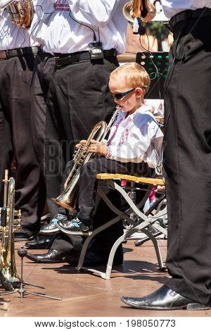 Buchlovice Czech Republic July 29 2017: Little boy plays trumpet at folk festivities. Gifted child. Traditional farmers harvest celebrations of garlic