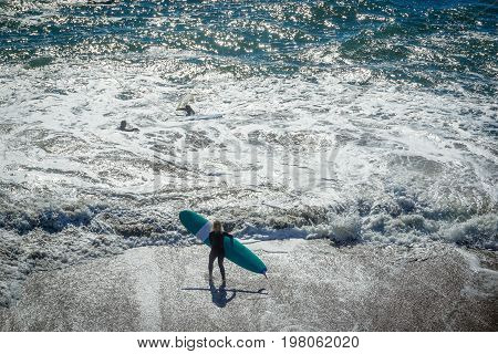 A surfer joins her friends in the waters of Capitola California