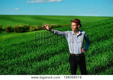 Man On The Field Shows On Elongated Hand Somewhere Far Into Something