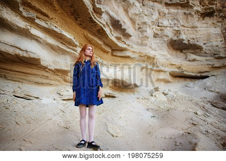 Beautiful Redheaded Girl Standing In A Blue Dress In The Middle Of A Sand Quarry