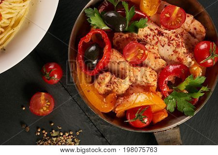 Fried chicken with vegetables on the pan and Italian pasta with a parmesan cheese basil olives paprica and tomatoes on a plate. Healthy food copncept. Top view copy space.