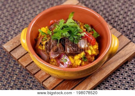 Grilled meat with raditional spanish rice decorated parsley in bowl on wooden board