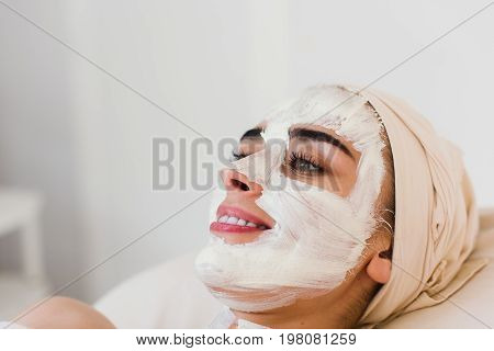 Spa facial mask application. Spa beauty organic facial mask application at day spa salon. Woman applying facial clay mask at spa salon, skincare, top view.