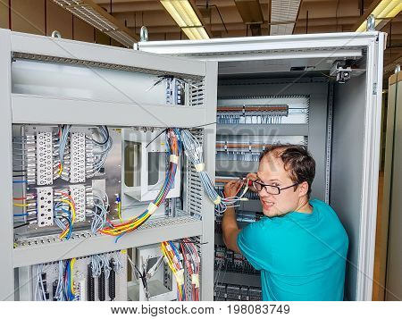 Electrical engineer configuring wires. Electrician repairing substation cubicle.