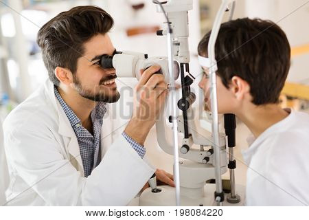 Optometrist examining patient in ophthalmology clinic with professional equipment