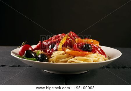 Delicious spaghetti bolognese with cheese onions olives and vegetables sauce with tomatoes carrots pepper paprika on a white plate. Healthy vegetarian food. Closeup