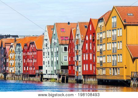 Famous wooden colored houses in Trondheim city Norway. Colorful houses on stilts in sunny day.
