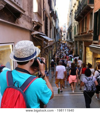 Young photographer takes a picture to people walking in the pedestrian zone