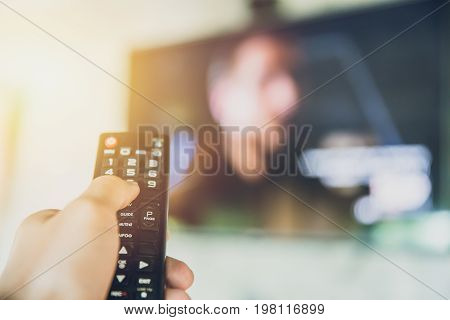 hand hold Smart TV remote control with a television blur background. change watching program channel