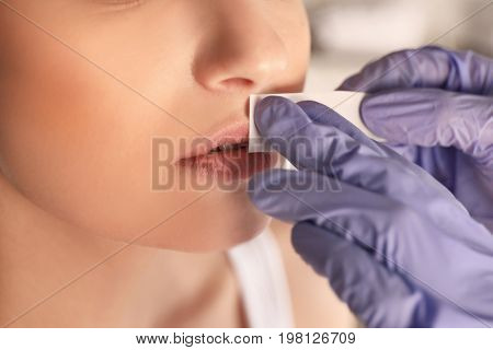Young woman undergoing epilation procedure on face in beauty salon, closeup