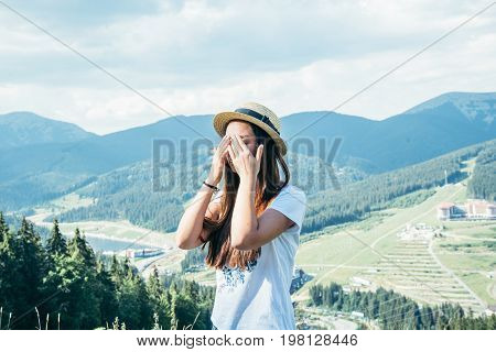 young pretty woman closing her yeys on the top of the mountain beautiful view on background