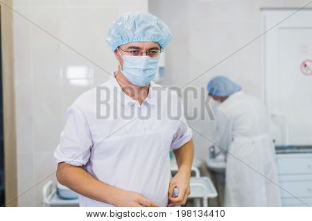 Thoughtful male surgeon wearing surgical mask in hospital.