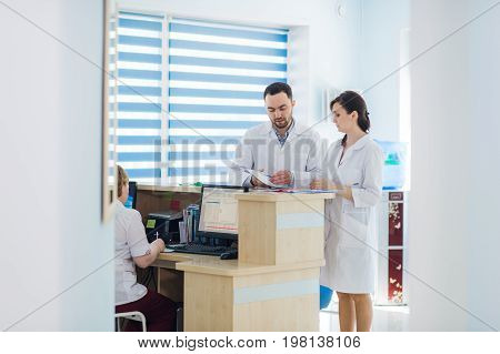 Busy reception in a hospital with doctors and receptionists.