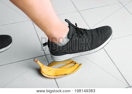 The guy stumbles on the peel of a natural, ripe, organic bright yellow banana on a gray background. Risk and danger concept. Accident and incident.