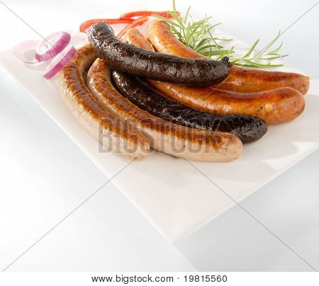 Weiße gebratene Wurst und gegrillte Blutwurst auf einem Teller mit weißen Hintergrund isoliert