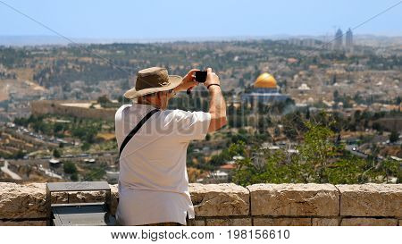 Tourist takes a photo of Jerusalem Old City view. Mount Scopus is a famous Holy Land place and it has a fantastic view to the Old Jerusalem. Jerusalem is a beautiful and popular touristic city.