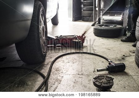 Mechanic rising a van. He is using a jack for tire change. Motion blurred