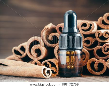 Essential cinnamon oil in brown glass small bottle with pipette on cinnamob sticks background. Copy space.