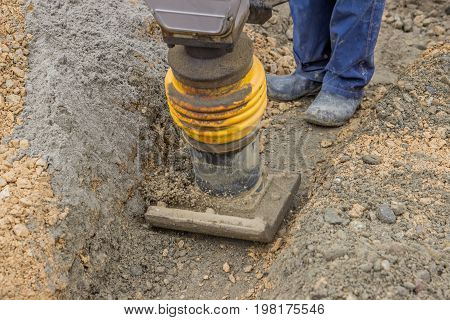 Worker Compacting The Sand Bedding With Mechanical Rammer