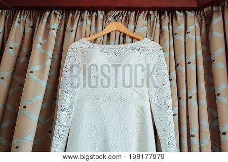 Bodice of a wedding dress hanging from a curtain pole. Bottom view