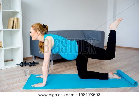 Pregnant woman doing physical exercises at home