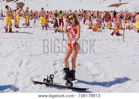 Sheregesh, Kemerovo region, Russia - April 22, 2017: Grelka Fest is a sports and entertainment activity for ski and snowboard riders in bikini in Russia, Sheregesh. Young happy pretty women on a snowboard in red bikini.