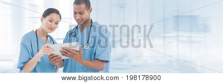 Digital composite of Doctors looking at a tablet against blue background