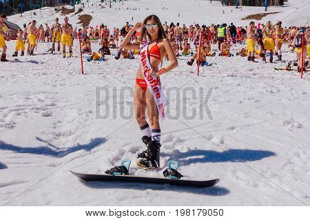 Sheregesh, Kemerovo region, Russia - April 22, 2017: Grelka Fest is a sports and entertainment activity for ski and snowboard riders in bikini in Russia, Sheregesh. Young happy pretty women on a snowboard in red bikini.