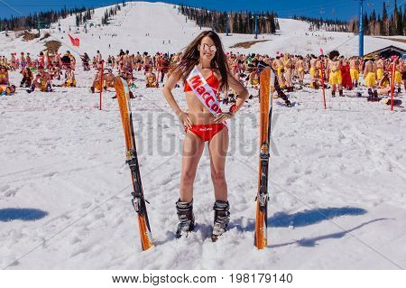 Sheregesh, Kemerovo region, Russia - April 22, 2017: Grelka Fest is a sports and entertainment activity for ski and snowboard riders in bikini in Russia, Sheregesh. Young happy pretty women with mountain ski in red bikini.