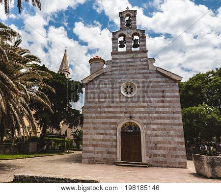 Church of Holy Trinity facade in Budva Old Town. Traditional stone church and paved square in Montenegro tourist capital.