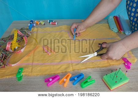 Tailor cutting fabric using large scissors or shears as he follows the chalk markings of the pattern close up of his hands. Woman's Hand Sewing Quilt