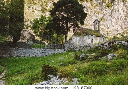 Ancient Serbian church ruins and mountain valley landscape near Kotor castle in Montenegro. Old mountain church and monastery in Kotor Bay region near hike path to Lovchen mountain. Saint Ivan chapel.