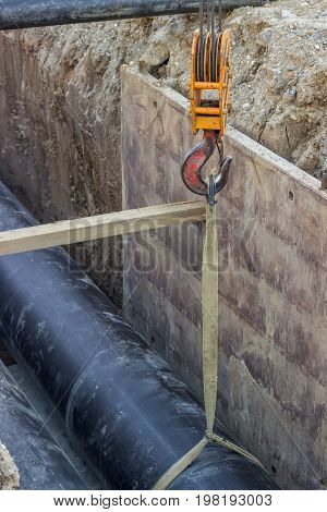 Crane Hook Hold Up Pipe In Trench