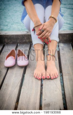 Young woman sitting on a wooden pier and enjoying the summertime.