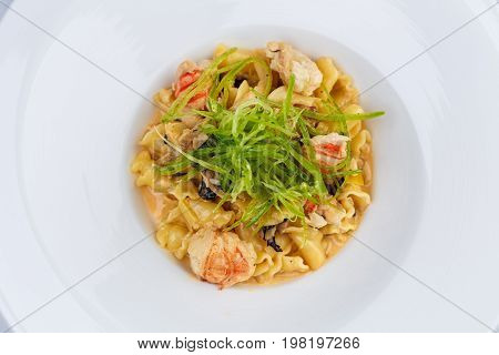 Ballerine pasta with shrimps in white plate on white tablecloth.