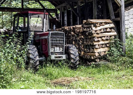 An old tractor front view in germany countryside old abandoned barn firewood wood stacked