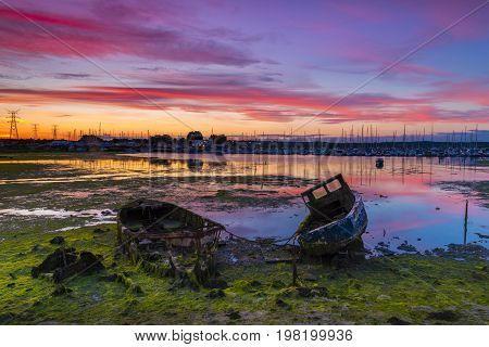 Derelict boats in the backwaters of Holes Bay Poole Harbour at low tide