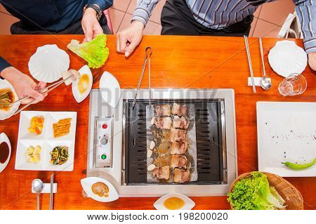 Process Of Cooking Korean Barbecue Raw Pork On The Tabletop Grill In Restaurant. Selective Focus. Cl