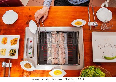 Process Of Cooking Korean Barbecue Raw Pork On The Tabletop Grill In Restaurant. Selective Focus. Cl