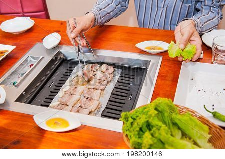 Korea Traditional Way Of Eating Grilled Dish In Korean Cuisine. Meat Is Served Raw, Then Cooked On T